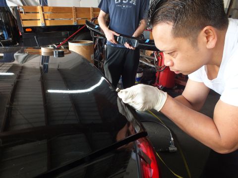 2003 Ford Crown Victoria - technician marks the trunk edge of a black sedan as a coworker checks a phone in the background.