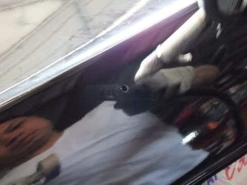2003 Ford Crown Victoria - Mirror-like black surface with a drilled hole reflects a technician and garage interior.