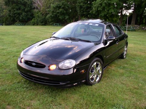 1998 Ford Taurus - A black 1998 Ford Taurus sedan is shown from a 3/4 front angle on a grassy lawn.