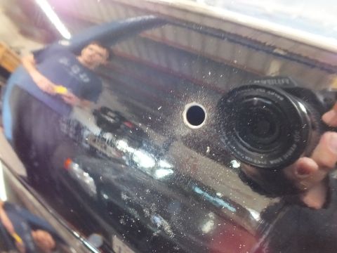 2003 Ford Crown Victoria - photographer's camera reflects in the black surface beside a freshly bored hole.
