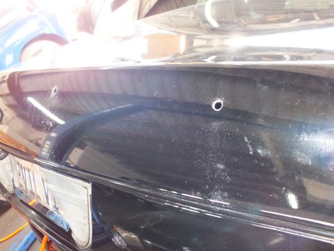 2003 Ford Crown Victoria - Rear deck of a black Ford Crown Victoria shows new holes above its plate frame.