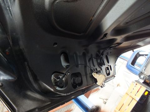 2003 Ford Crown Victoria - Inner face of a raised black trunk lid reveals its stamped reinforcement and latch area.