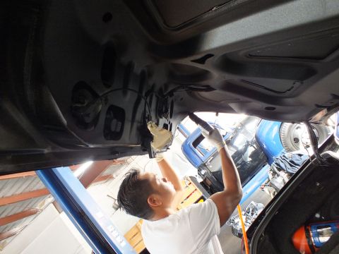 2003 Ford Crown Victoria - technician fastens hardware on the inner panel of an open black trunk lid.