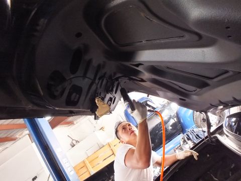 2003 Ford Crown Victoria - Technician runs an air tool against the inner face of a black trunk lid overhead.