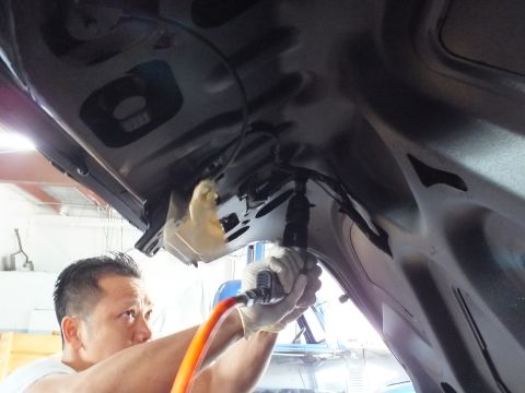 2003 Ford Crown Victoria - Worker aims an air-hose spray tool at the inner panel of a dark vehicle, masking paper visible nearby