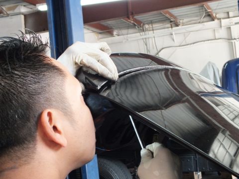 2003 Ford Crown Victoria - Close inspection of a black sedan's painted trunk lid while raised on a lift in a repair shop