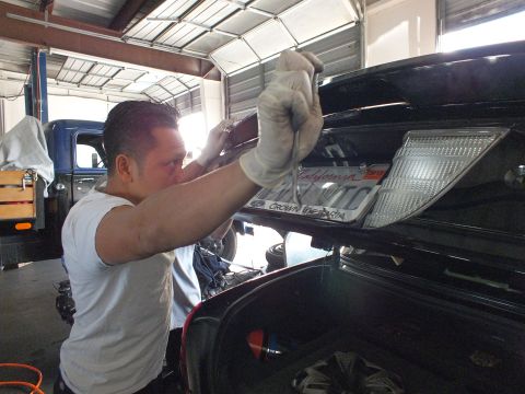 2003 Ford Crown Victoria - Technician at the open trunk of a black Crown Victoria showing a California license plate