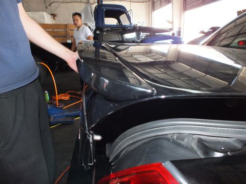 2003 Ford Crown Victoria - Rear corner of a black car with exposed taillight and shop cabling on the floor