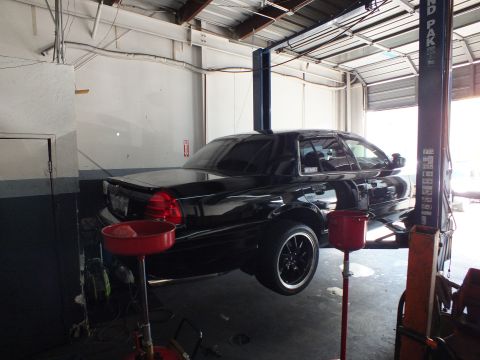 2003 Ford Crown Victoria - Black Crown Victoria lifted in a garage, rear taillights and black wheels visible