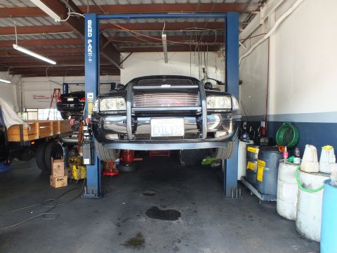 2003 Ford Crown Victoria - Black sedan raised on a Bend Pak lift showing chrome brush guard and EVIL VIC plate