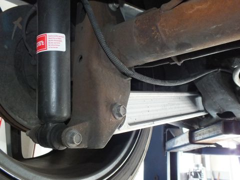 2003 Ford Crown Victoria - Underbody view of a rear shock, exhaust pipe and aluminum brace beside the wheel