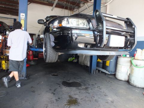 2003 Ford Crown Victoria - Black sedan lifted high on a two-post hoist showing front bumper and brush guard