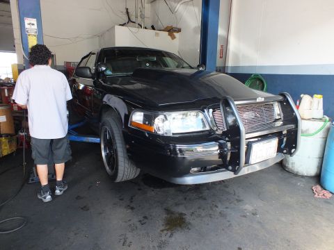 2003 Ford Crown Victoria - Front three-quarter view of a black Crown Victoria on a hoist with brush guard installed