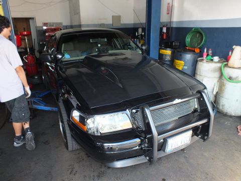 2003 Ford Crown Victoria - Black Crown Victoria raised on a hoist showing chrome brush guard and EVIL VIC plate