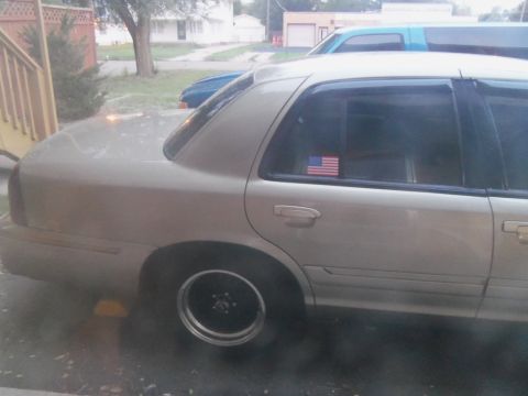 2000 Mercury Grand Marquis - A gold sedan is parked outside with another vehicle visible in the background.