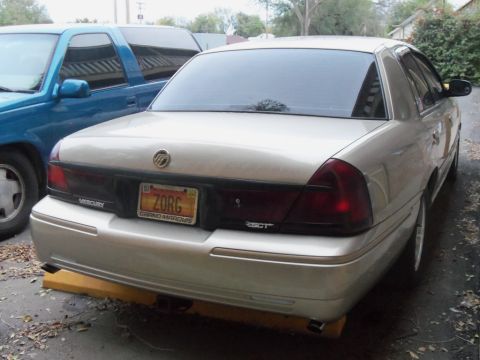 2000 Mercury Grand Marquis - Rear view of a 2000 Mercury Grand Marquis, parked next to a blue pickup truck.