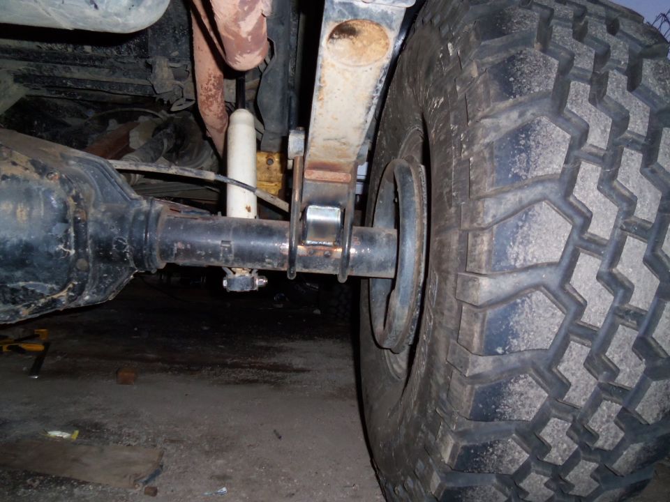 Close-up of a vehicle's rear axle, leaf spring, and tire