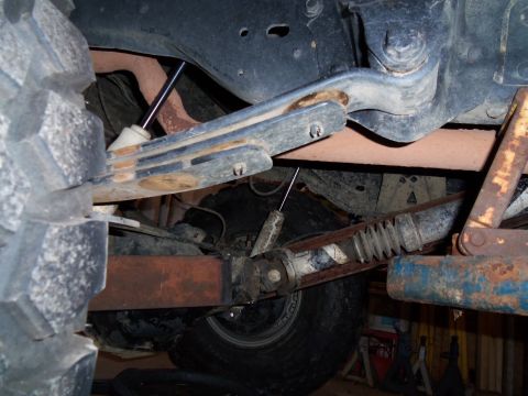1989 Ford Bronco - Undercarriage view of suspension components and a large tire, showing rust and wear.
