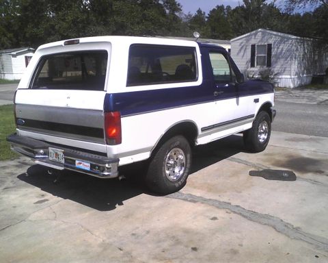 1996 Ford Bronco - This two-tone Ford Bronco is parked on a concrete driveway in front of a mobile home.