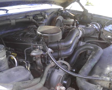 1996 Ford Bronco - Engine bay of a 1996 Ford Bronco, showing the air intake system and alternator.
