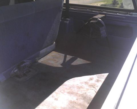 1996 Ford Bronco - The rear cargo area of the vehicle shows a folded seat and a spare tire cover.