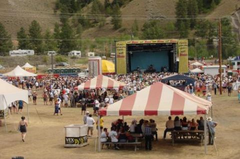 1990 Ford Bronco - A large outdoor gathering with a stage and audience, surrounded by tents and RVs.