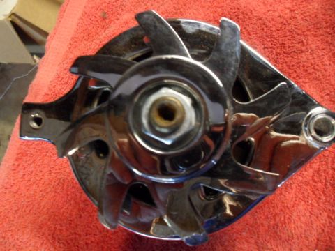1994 Jeep Cherokee - Close-up of a chrome alternator with visible fan blades, resting on a red cloth. Text at the bottom reads "SUPERMOTORS www.supermotors.net".