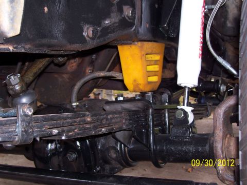 1990 Ford Bronco - Undercarriage view shows suspension and steering parts, including a yellow bump stop and a white shock absorber.