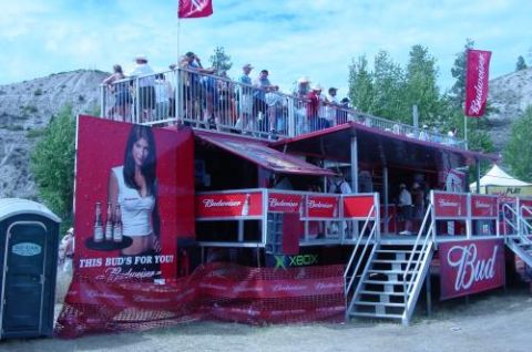 1990 Ford Bronco - A multi-level Budweiser promotional stand is set up outdoors with people on the upper level and branding visible throughout.