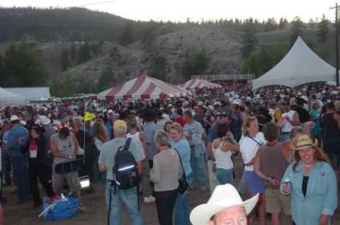 1990 Ford Bronco - A large gathering of people are enjoying an outdoor event, with tents set up and hills in the distance.