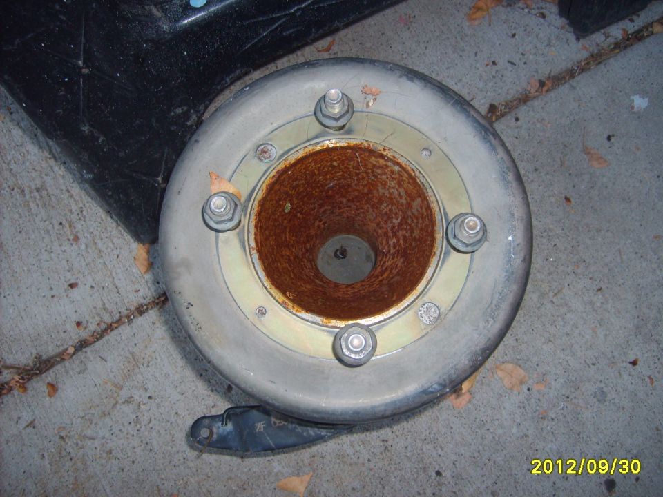 Round metal drum-like part with rusted center bore and four hex nuts, on concrete, dated 2012/09/30