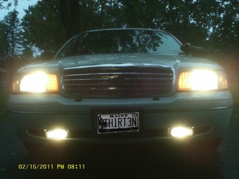 1998 Ford Crown Victoria - A 1998 Ford Crown Victoria is shown from the front, with its headlights and fog lights illuminated.