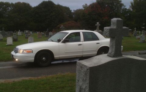 1998 Ford Crown Victoria - White 1998 Ford Crown Victoria parked on a road within a cemetery.