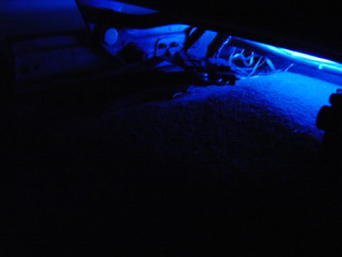 1999 Ford Taurus - Blue underglow lighting illuminates the carpet and underside of a car seat, with visible wiring and structural components.
