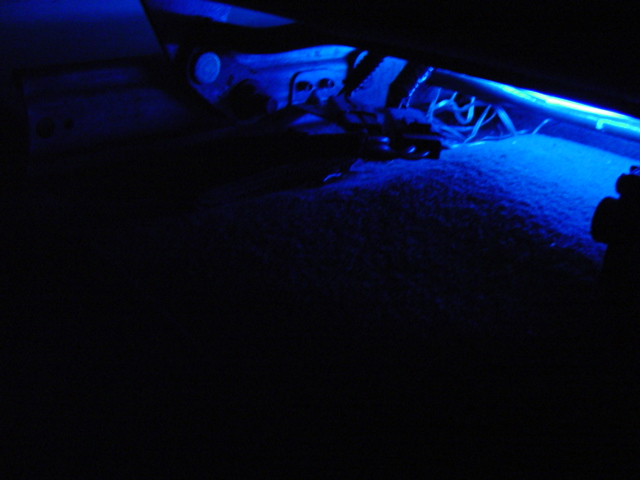 Blue underglow lighting illuminates the carpet and underside of a car seat
