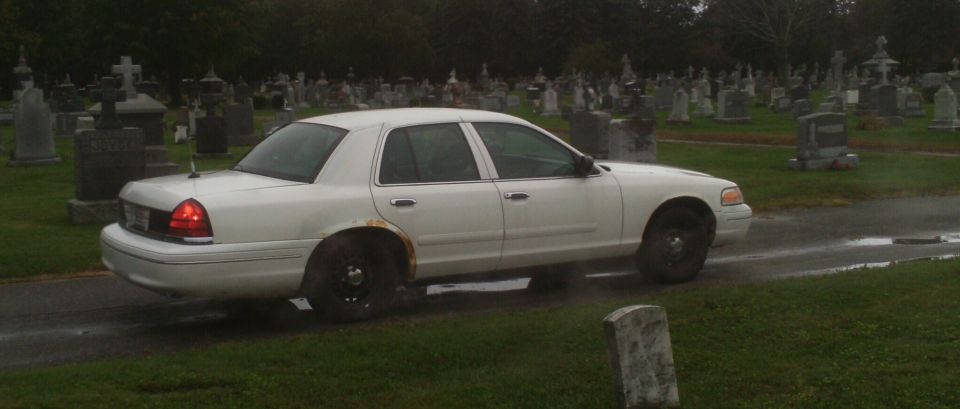 White 1998 Ford Crown Victoria driving through a cemetery
