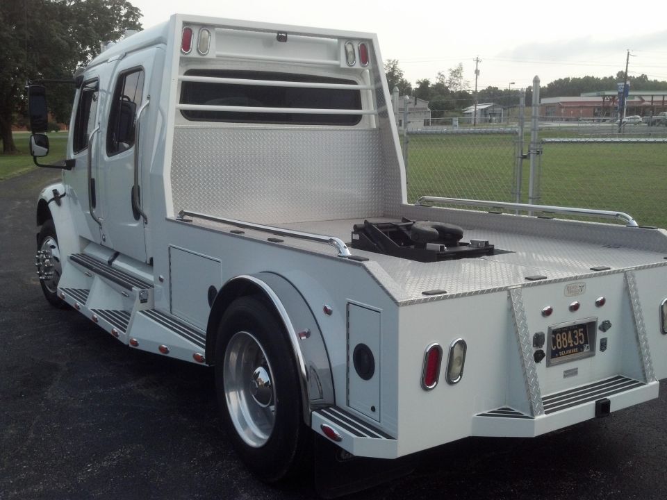 White flatbed truck with fifth wheel hitch, rear quarter view
