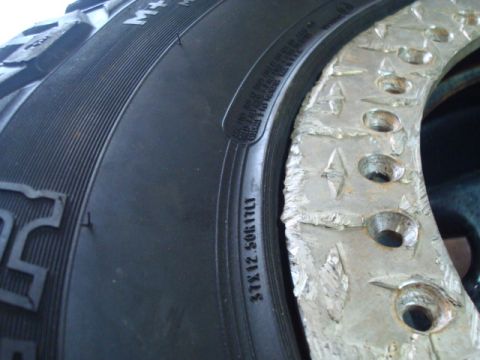 1995 Ford Bronco - Close-up of a tire and a damaged wheel, showing tire size and wheel damage.
