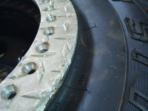 1995 Ford Bronco - A close-up shows a tire next to a damaged beadlock wheel with diamond plate texture.