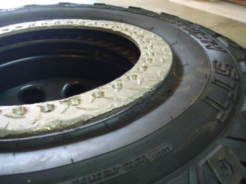 1995 Ford Bronco - A beadlock ring with numerous bolt holes is mounted on a tire, showing a close-up view of the wheel assembly.