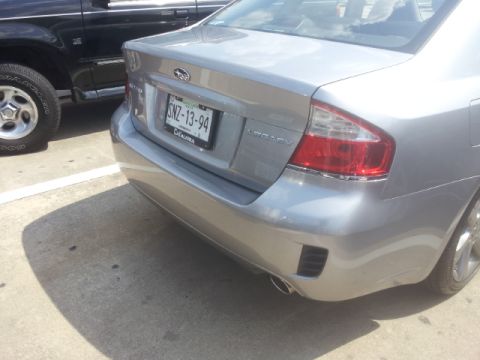 2008 Subaru Legacy - The rear of a silver Subaru Legacy sedan is visible, parked next to a black SUV.