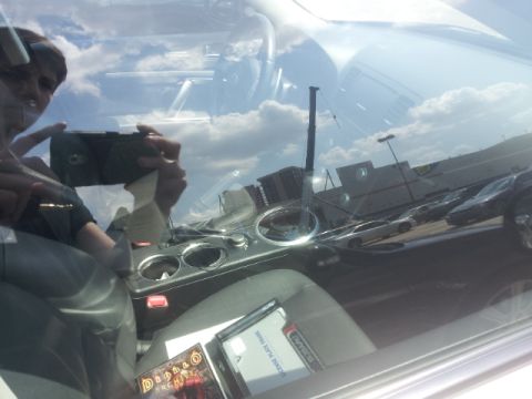 2008 Subaru Legacy - A person takes a selfie inside a car, reflecting the sky and other vehicles in the parking lot.