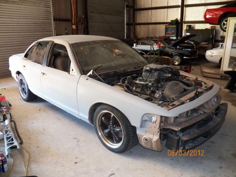 1993 Ford Crown Victoria - This 1993 Ford Crown Victoria is undergoing work in a garage, with its engine exposed.