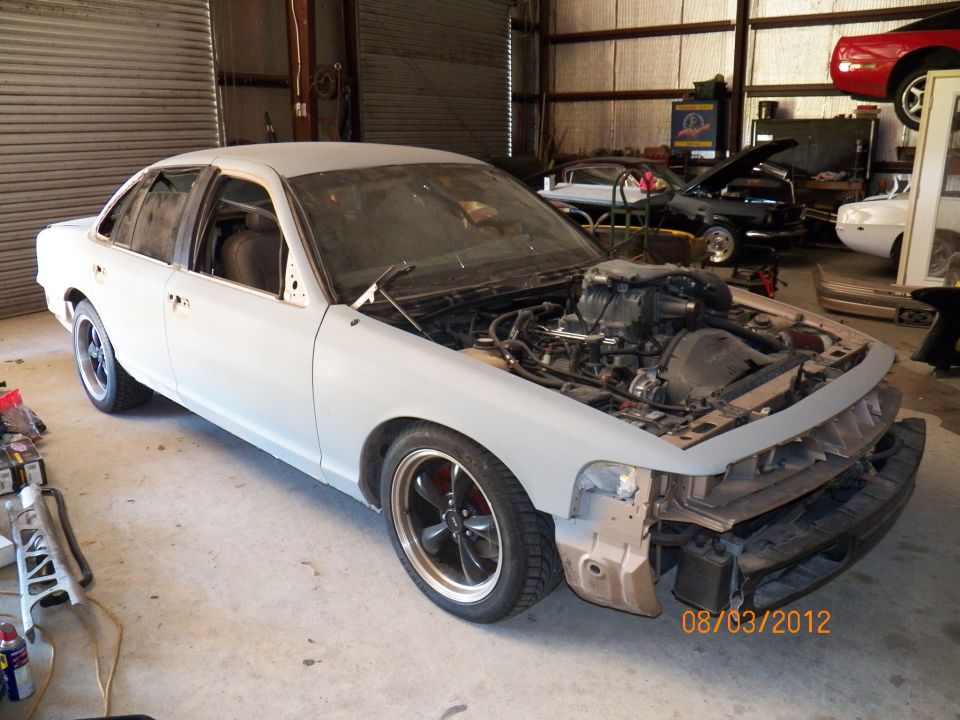 1993 Ford Crown Victoria in garage, hood open, showing engine. Other cars visible in background