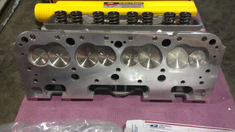 1973 Chevrolet Camaro - An aluminum engine cylinder head with valve springs is shown, with a yellow cover in the background.