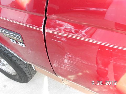 1994 Ford Bronco - The side of a red 1994 Ford Bronco shows significant damage from a side-swipe incident.