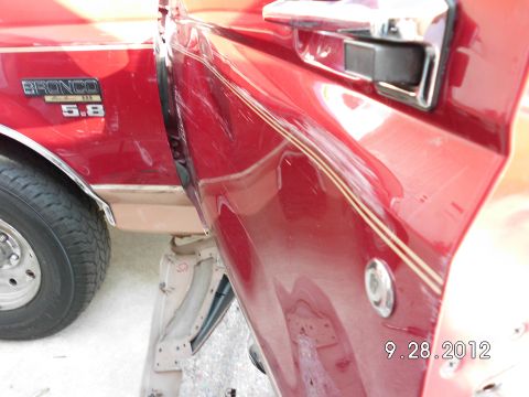 1994 Ford Bronco - Close-up of the side door of a red 1994 Ford Bronco, showing the 'Bronco 5.8' badge and chrome door handle.