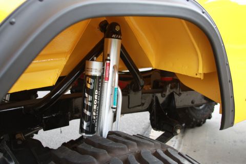1970 Ford Bronco - Close-up view of the suspension system and tire within the wheel well of a yellow vehicle.