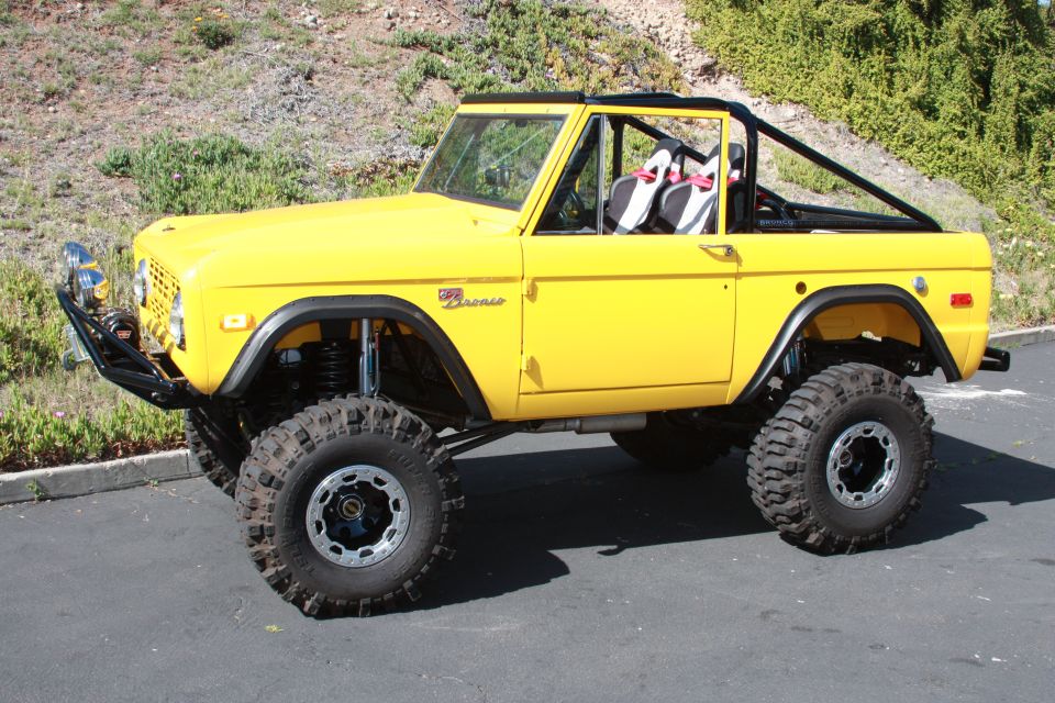 Yellow 1970 Ford Bronco with a lift kit, large tires, and a roll cage