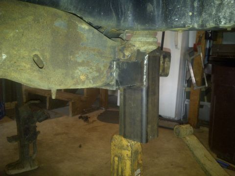 1995 Ford Bronco - Custom metal bracket welded onto a vehicle's frame, held up by jack stands.